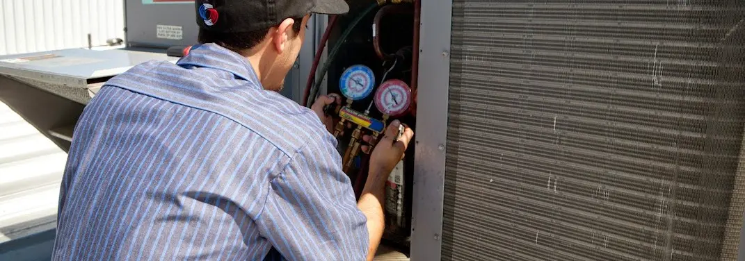 HVAC technician servicing a condenser unit in Pennsauken